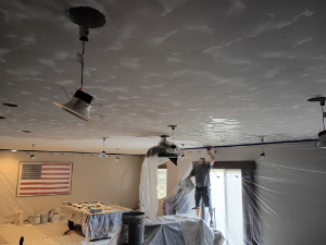 a drywaller putting mud on a ceiling